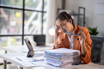 Asian accountant woman having headache after working with financial documents