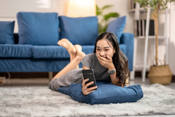 Fototapeta premium Young woman lying on floor using smartphone and having fun