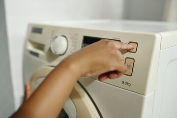 A hand adjusting settings on a modern washing machine with precise control panel displayed. Focused...