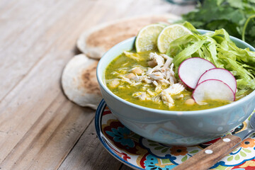 Traditional mexican green pozole soup on wooden table. Copy space