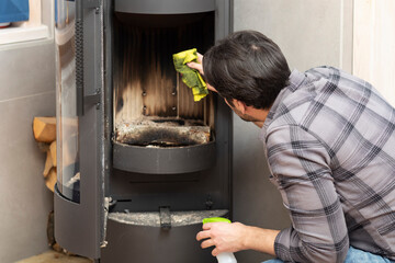 A young man cleans a fireplace to be prepared for the harsh winter during an energy crisis	