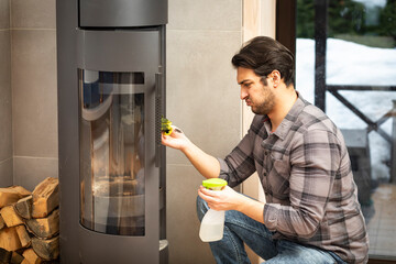 A young man cleans a fireplace to be prepared for the harsh winter during an energy crisis	