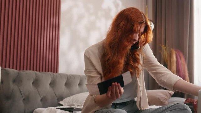 Angry mad stressed ginger female woman girl lady at home bedroom bed preparing trip vacation travel holiday problem trouble mistake tickets passport failure talking mobile phone argue looking laptop