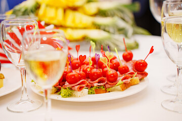A plate of bread, lettuce, sausage and cherry tomato canapes on a served table. appetizers for the banquet.