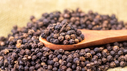 extreme closeup of black pepper kept on a wooden spoon