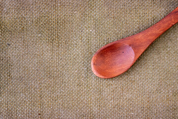 A empty wooden spoon on a brown background