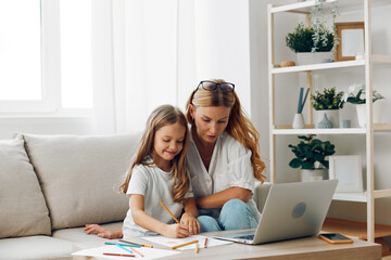 Mother and daughter bonding on the couch while exploring new adventures online with a laptop in a cozy home setting