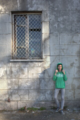 a guy in a green hoodie and glasses on the background of a building