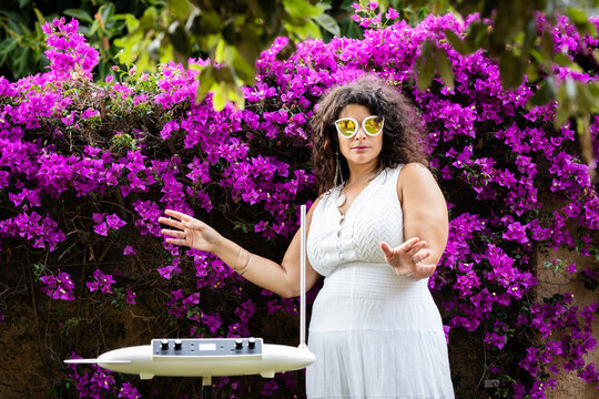 Beautiful Woman in White Dress Playing the Theremin in Scenic Garden Setting