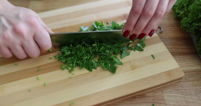 Chop fresh parsley on a wooden cutting board