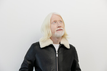 Man with long white hair and beard wearing a black leather jacket, looking up against a simple white background Expressions of curiosity and contemplation are evident