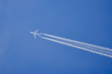 a passenger plane in the blue sky that leaves traces