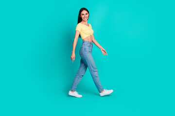 Full body profile portrait of pretty young woman walk empty space wear top isolated on turquoise color background