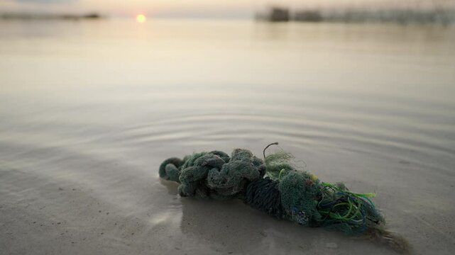 plastic rope waste in ocean, marine debris washed ashore on beach