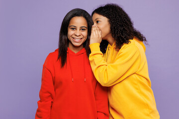 Two young little kid teen girls women they wearing red yellow hoodie casual clothes whisper gossip...