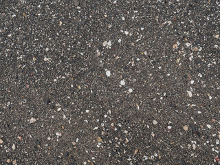 Black micro stones and sea shells sand beach as a background