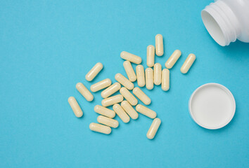 Oval white capsules on a blue background. Medical pills, top view