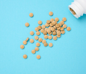 Yellow round pill for healthcare. Medical treatment, blue background, top view