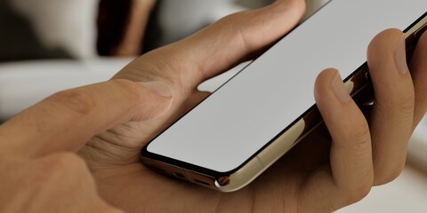 Caucasian White middle aged male using smartphone with a blank white screen. Living room, interior design, modern apps mockup. Vertical phone orientation