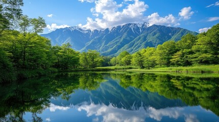 A stunning view of Kamikachiaes Azusa River reflecting the fresh green trees and the majestic Hotaka Mountains, creating a peaceful and picturesque landscape.