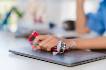 Fototapeta premium Doctor's Hands Holding Stethoscope on Laptop