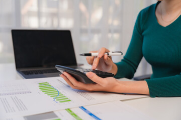Focused on Financial Success: A close-up shot of a woman's hand using a calculator, her focus and determination evident as she analyzes financial data, symbolizing a commitment to financial success.