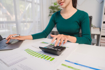 Focused Finance Professional: Woman using calculator and laptop to analyze financial data 