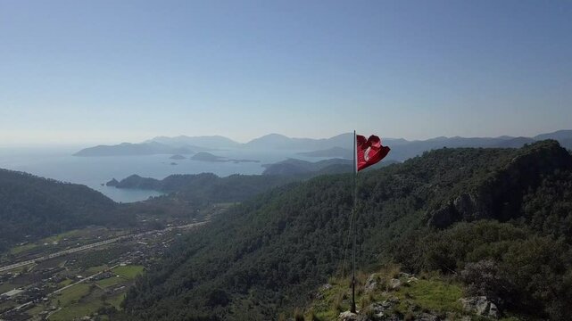Drone video of G&ouml;cek from top of a surrounding mountain with Turkish flag in Fethiye Muğla 