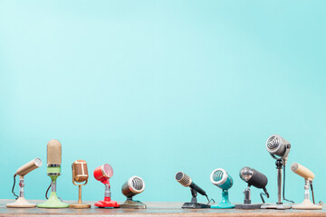 Microphones for press conference or interview on vintage table front mint blue background. Retro...