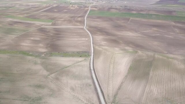 Drone view of a wide field of agriculture crossed by a beautiful road with a moving truck 