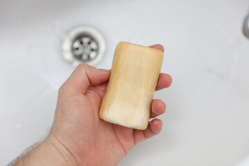 Man's hand holding soap over the sink