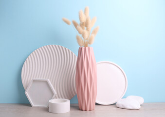 Minimalistic vase in Scandinavian style with dried lagurus flower and plaster trays on the table, blue background