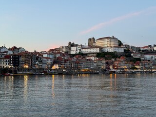 A captivating view from Vila Nova de Gaia across the Douro River, showcasing Porto's vibrant, colorful buildings glowing under the warm hues of a stunning sunset.