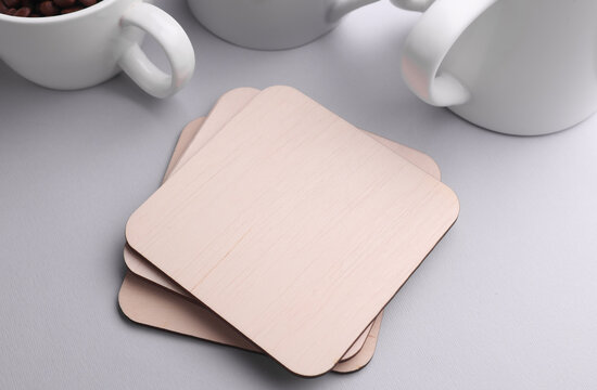 Wooden square drink coasters and cups on gray background