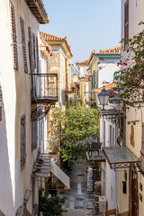 Stroll through the picturesque narrow alley of Nafplio, Greece, where colorful buildings adorned with balconies showcase local flora, inviting tranquility and exploration.