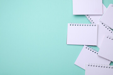 Group of Blank white spiral notebooks on mint green background with copy space