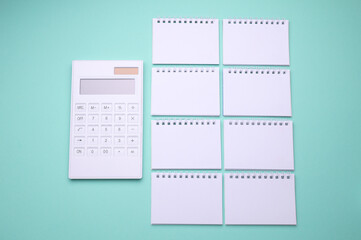 Group of Blank white spiral notebooks with calculator on mint green background