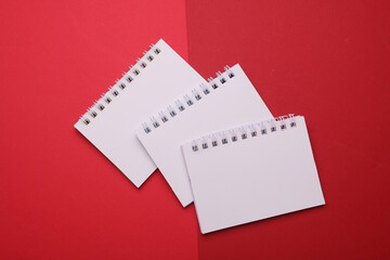 Group of white blank spiral notebooks on red background