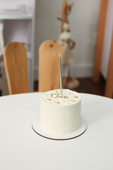 cake first birthday.white cake with the word one , with one candle on a white table . festive 