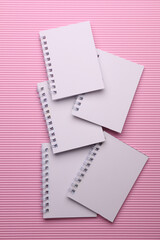 Group of white blank spiral notebooks on pink background