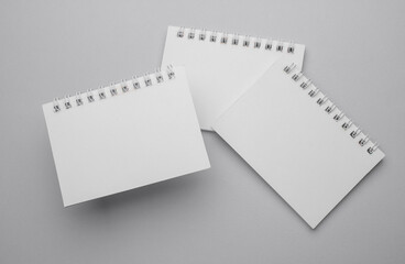 Group of white blank spiral notebooks on gray background