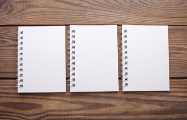 Group of white blank spiral notebooks on wooden background