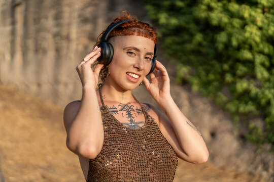 Smiling informal woman listening to music during summer