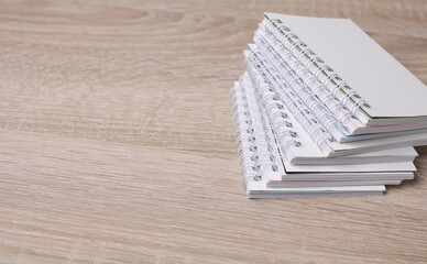 Stack of white blank spiral notebooks on table