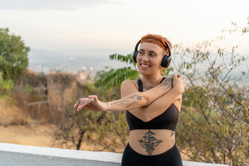 Happy woman in activewear stretching arms at sunrise