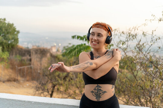 Happy woman in activewear stretching arms at sunrise