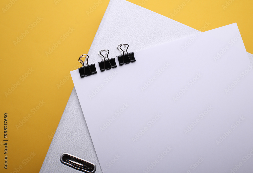 Poster white sheet of paper with binders and folder on yellow background