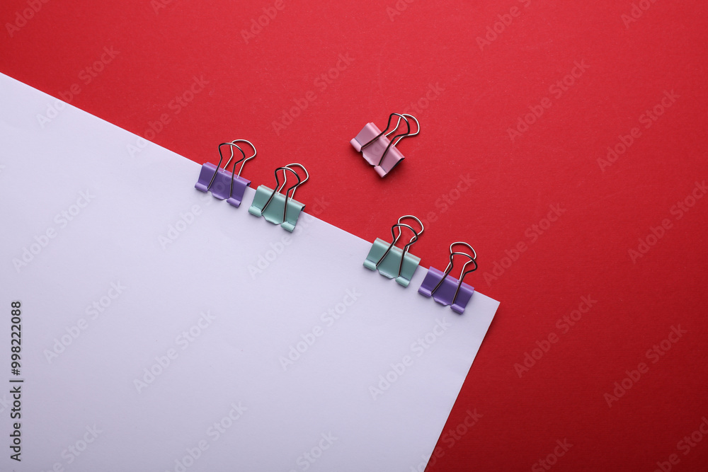 Poster white sheet of paper with colored binders on red background