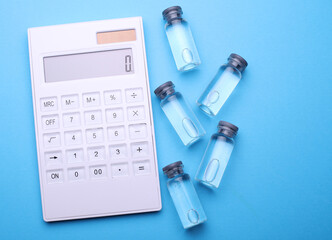 Calculator and Medical glass vials with liquid on a blue background