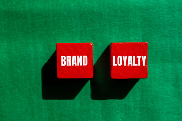 Brand loyalty message written on red wooden cubes with green background. Conceptual brand loyalty symbol. Copy space.